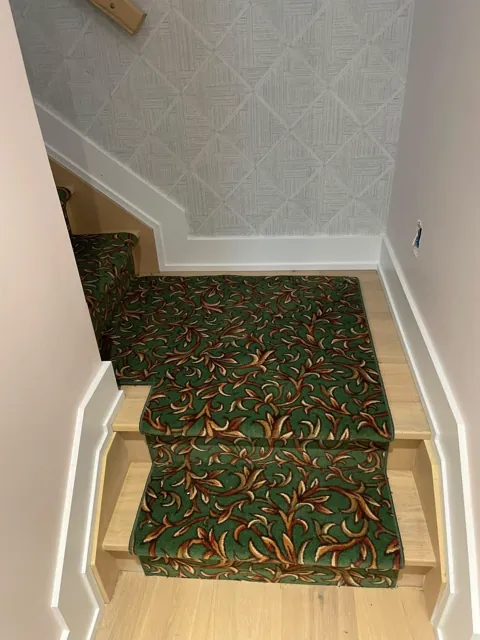 View down a staircase fitted with a green leaf-patterned carpet runner